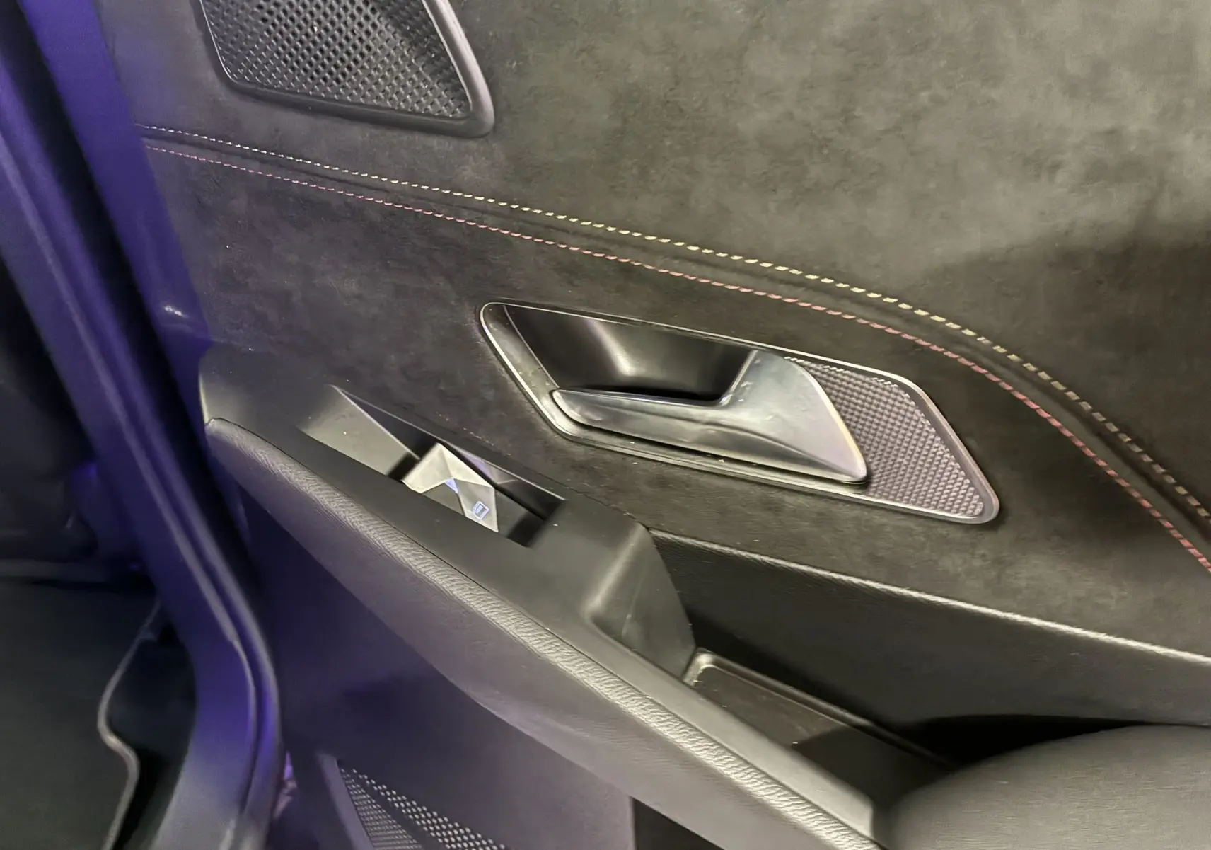 Gros plan sur la poignée intérieure et la commande de vitre de la porte côté gauche du DS7 E-TENSE gris, finition Performance Line.