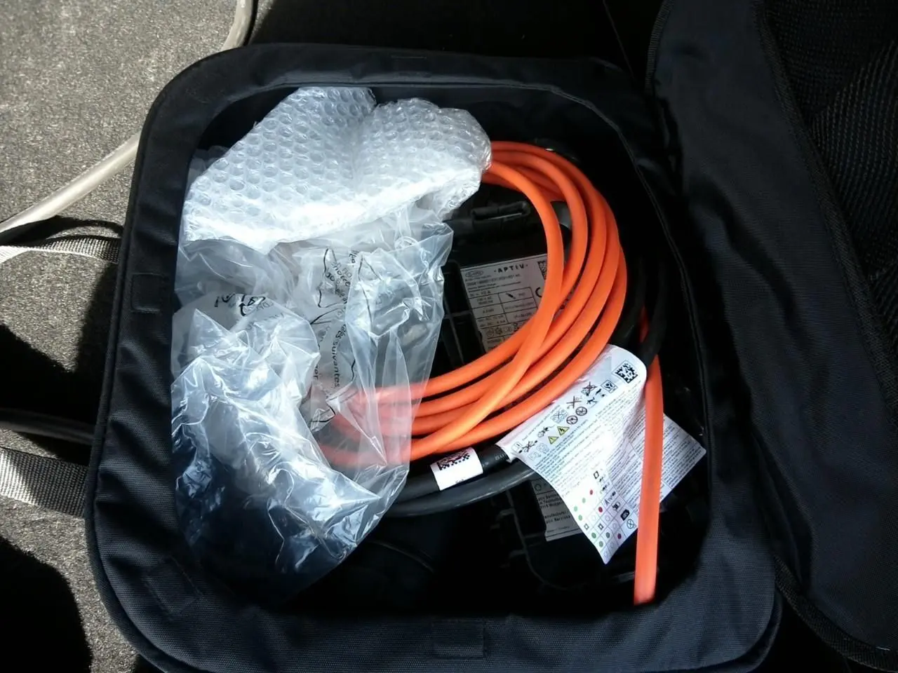 Vue rapprochée d’un câble de recharge orange dans un sac noir, accessoire du DS7 E-TENSE gris 2024.