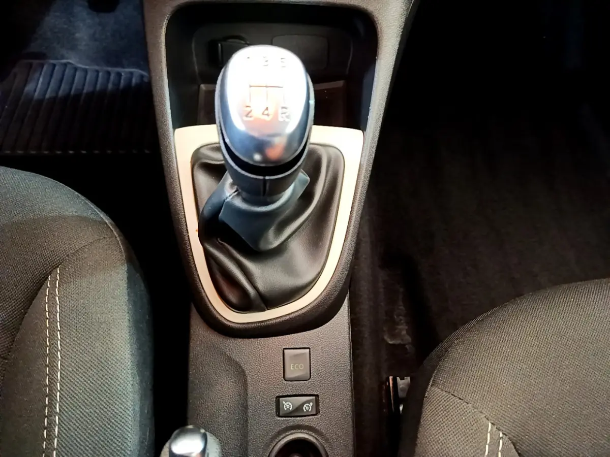 Gros plan sur le levier de vitesses manuel gris et noir du Renault Captur Business, entouré des sièges avant en tissu foncé.