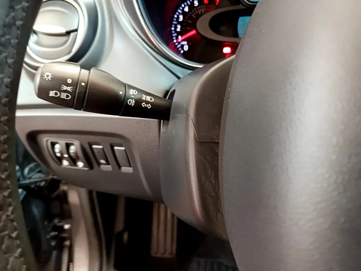 Gros plan sur la manette des phares et clignotants à gauche du volant cuir du Renault Captur Business gris foncé, intérieur.