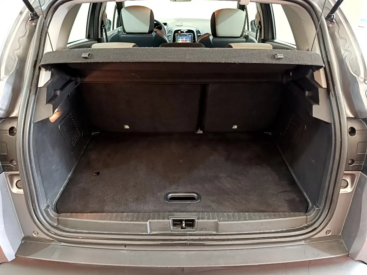 Coffre ouvert vu de l'arrière d'un Renault Captur gris foncé, montrant la banquette arrière et l'écran tactile du tableau de bord.
