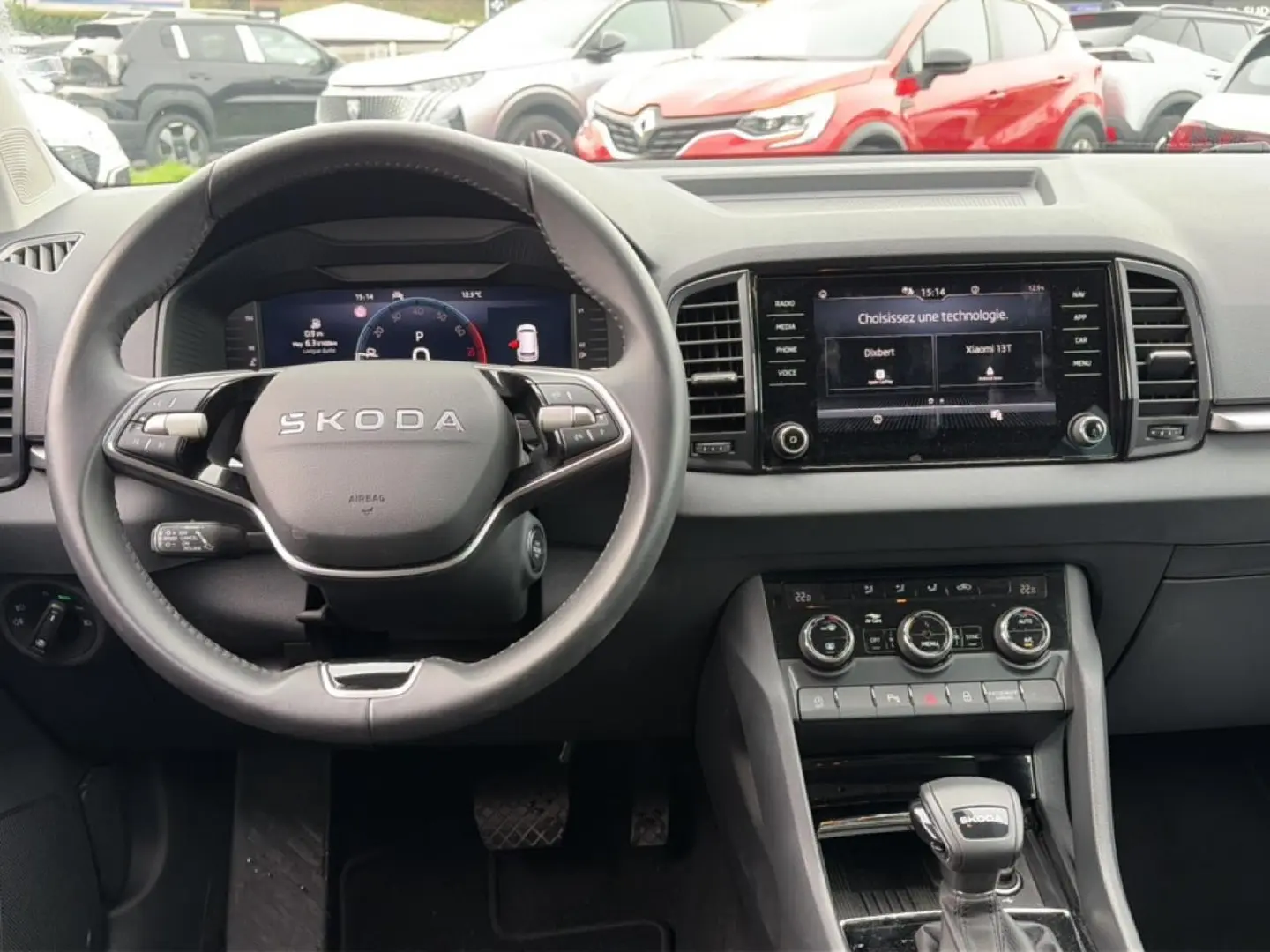 Vue intérieure centrée sur le volant SKODA noir et l'écran tactile du tableau de bord du Karoq 2025.