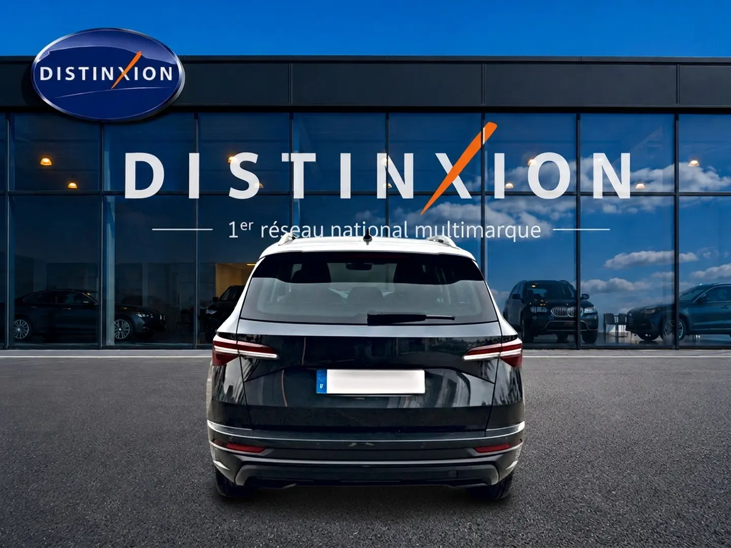 Vue arrière d'un Skoda Karoq noir 2025 garé devant une vitrine avec logo Distinxion.