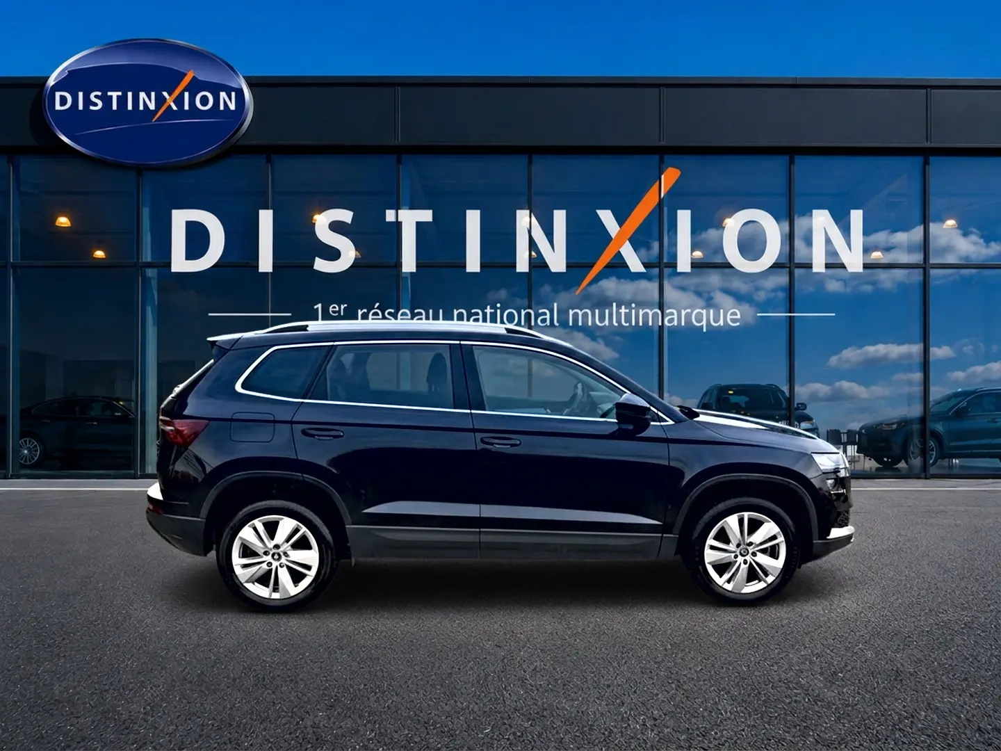 Vue latérale droite d'un Skoda Karoq noir 2025 garé devant une vitrine avec logo Distinxion.