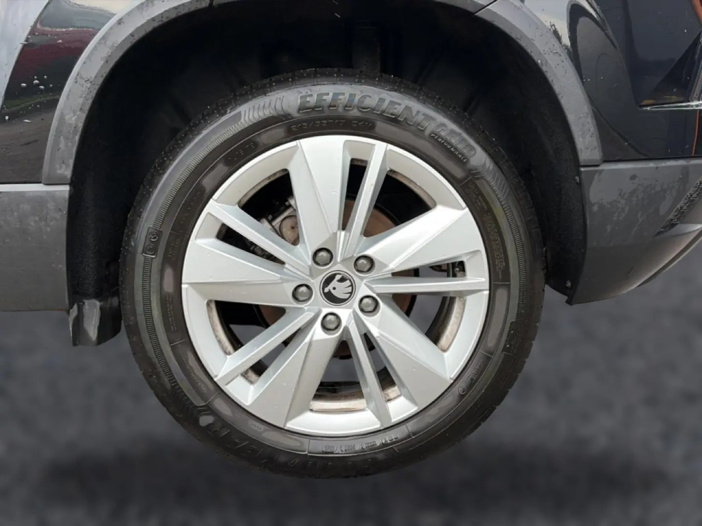 Gros plan sur la roue avant droite du Skoda Karoq noir, mettant en valeur la jante alu argentée et le logo central.