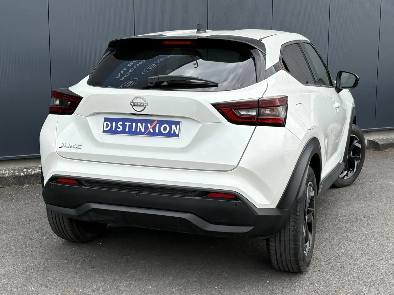 Vue 3/4 arrière droite du Nissan Juke blanc perle 2024 avec jantes alliage noires et vitres teintées.