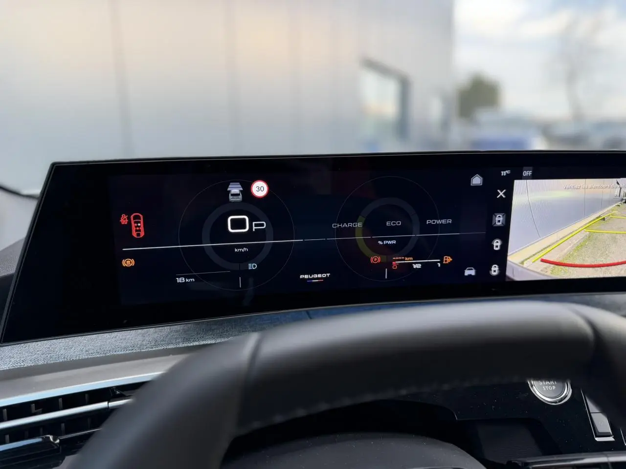 Vue rapprochée du tableau de bord numérique panoramique 21 pouces du Peugeot 3008 Hybrid blanc, affichant la caméra de recul.
