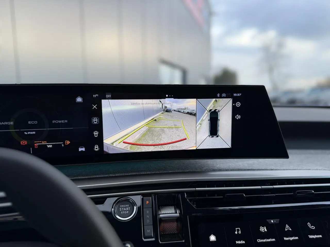 Vue intérieure du tableau de bord du Peugeot 3008 Hybrid blanc, écran panoramique affichant caméra 360° et vue arrière.