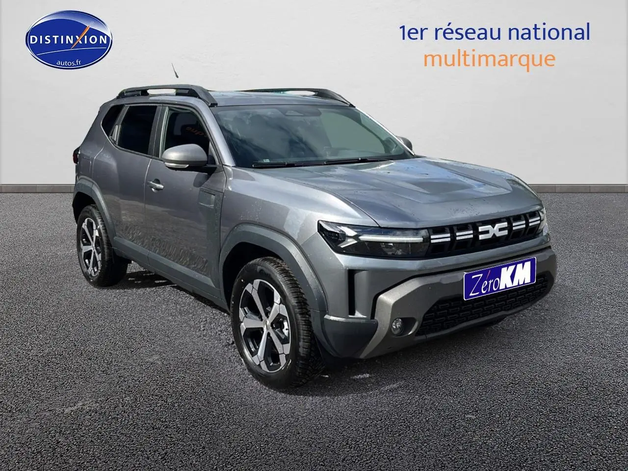 SUV Dacia Duster gris schiste vu en 3/4 avant droit avec barres de toit et jantes alu distinctives.