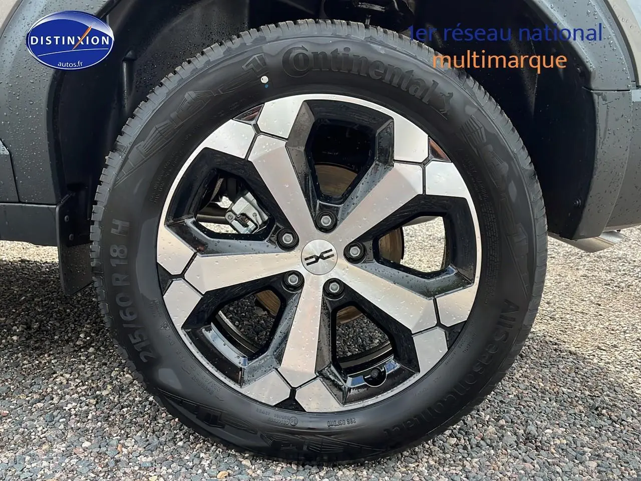 Gros plan sur la jante alu bicolore d’un Dacia Duster gris schiste, avec pneu Continental visible côté arrière droit.