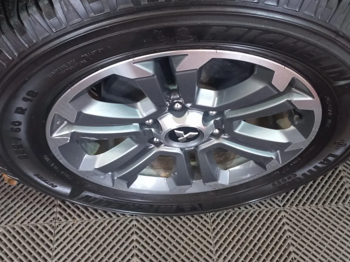 Gros plan sur la jante aluminium gris foncé d’un Mitsubishi L200 avec pneu Michelin Cross 255/60 R18.