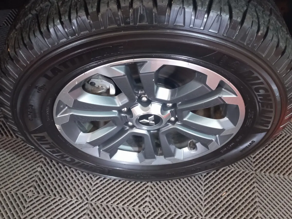Gros plan sur la roue en alliage gris du Mitsubishi L200 avec pneu Michelin visible sur un sol texturé.