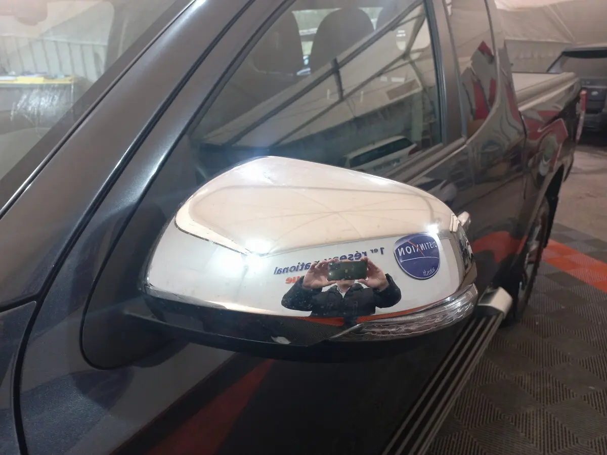 Rétroviseur droit chromé du Mitsubishi L200 gris foncé, vue rapprochée sur la porte avant côté conducteur.