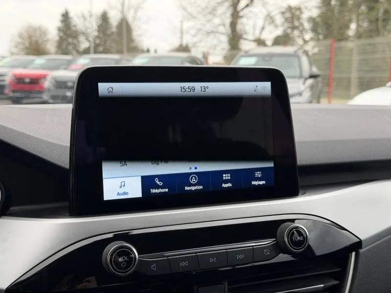 Écran tactile central du tableau de bord du Ford Kuga 2024, avec commandes audio et navigation visibles.