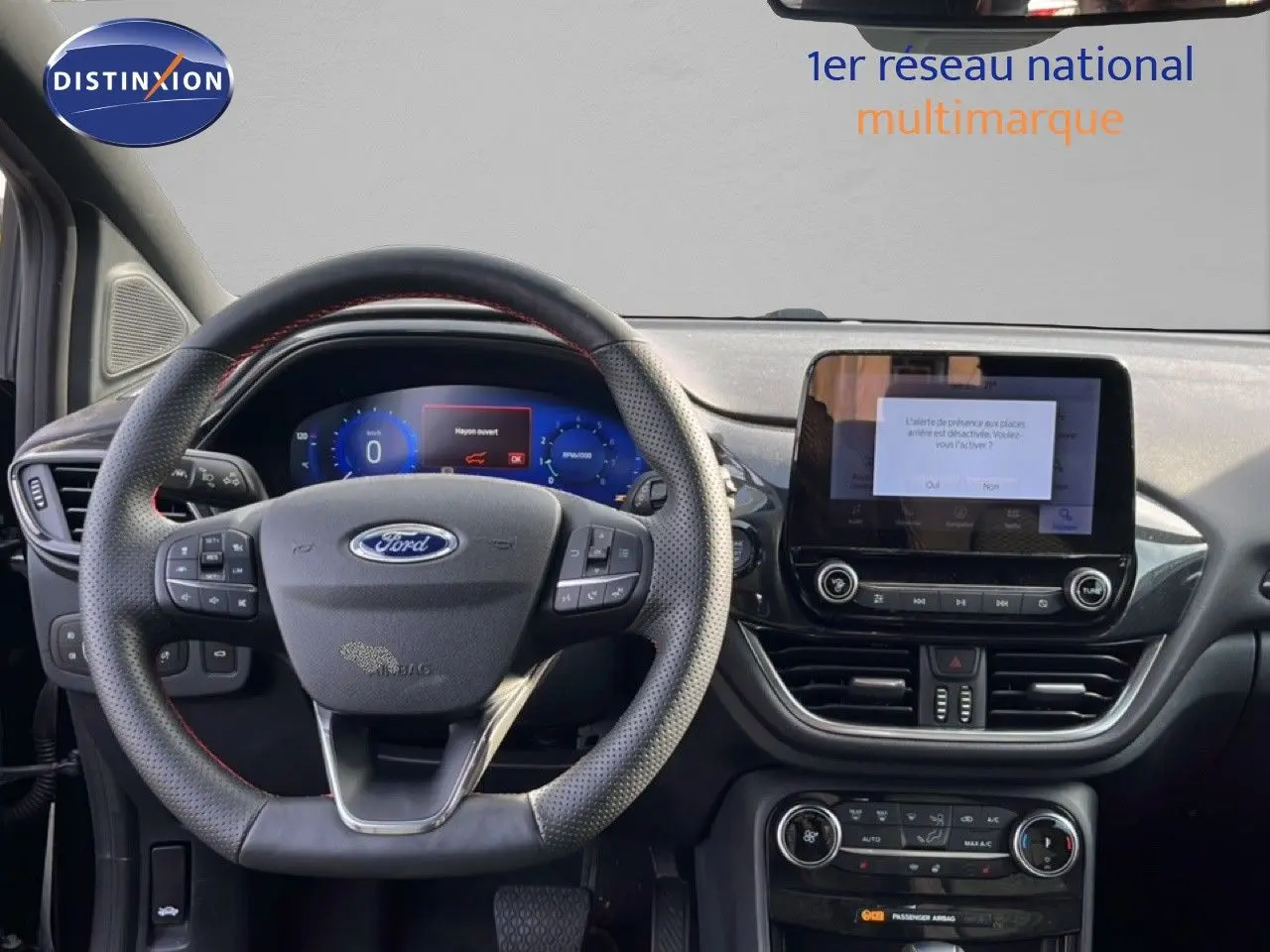 Vue intérieure du tableau de bord et volant noir perforé de la Ford Puma 2023 avec écran tactile central allumé.