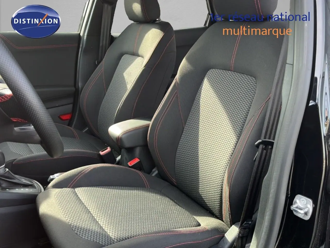 Vue intérieure côté avant droit du Ford Puma noir Agate Metal, mettant en valeur les sièges tissu noir avec surpiqûres rouges.