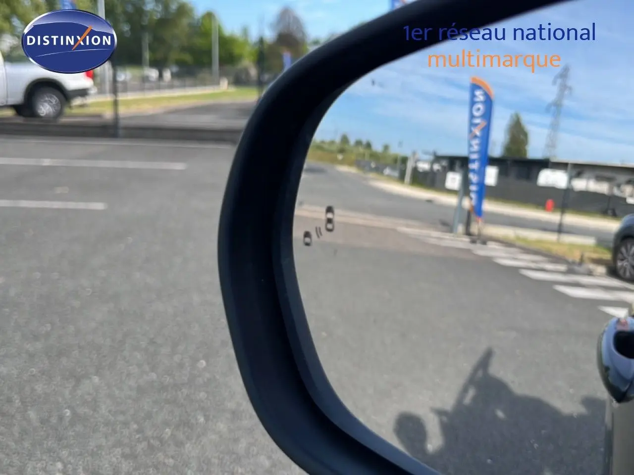 Rétroviseur extérieur droit d’un Ford Puma noir agate métal, avec vue sur un parking et une bannière Distinxion en arrière-plan.