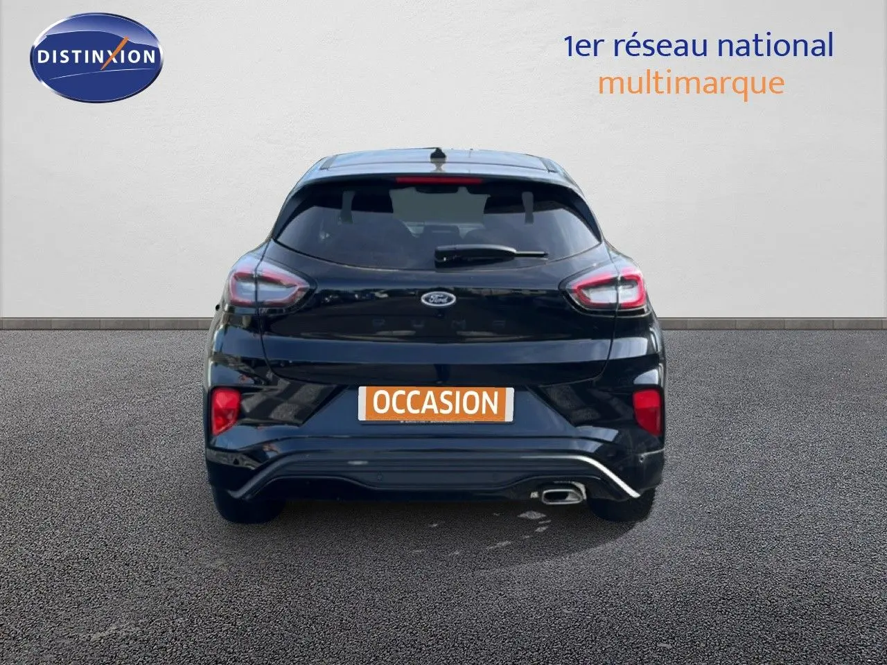 Vue arrière d'un Ford Puma noir Agate Métal 2023 avec feux LED et sortie d'échappement visible sur un sol bitumé.