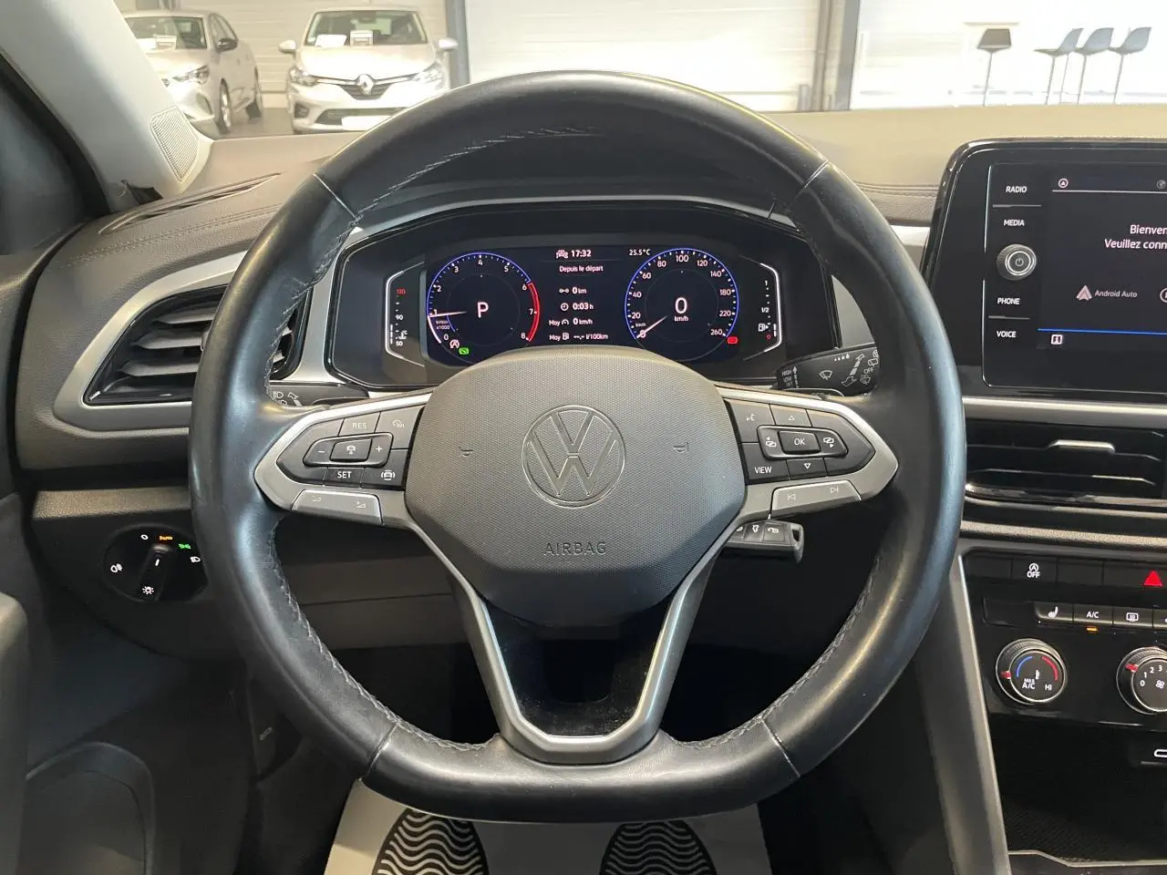 Vue intérieure centrée sur le volant cuir noir multifonction du Volkswagen T-Roc 2022 avec tableau de bord digital.