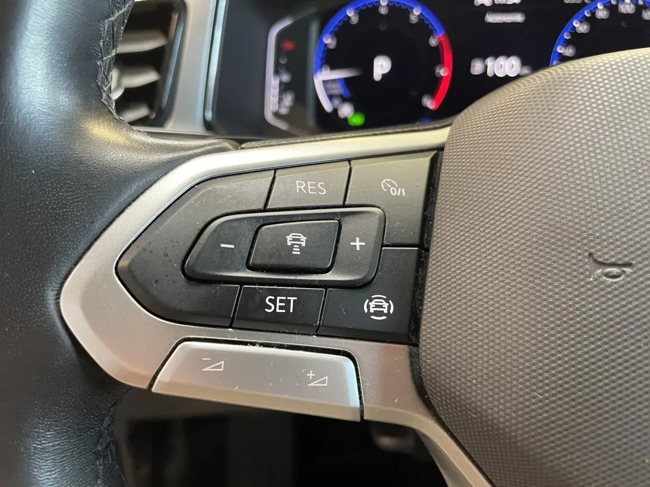 Gros plan sur les commandes de régulateur de vitesse au volant cuir noir du Volkswagen T-Roc 2022.