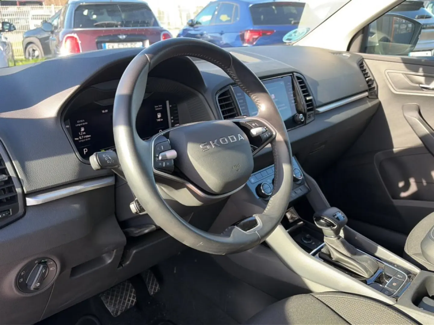 Vue intérieure côté conducteur du Skoda Karoq gris 2025, volant cuir multifonction et écran tactile central visible.