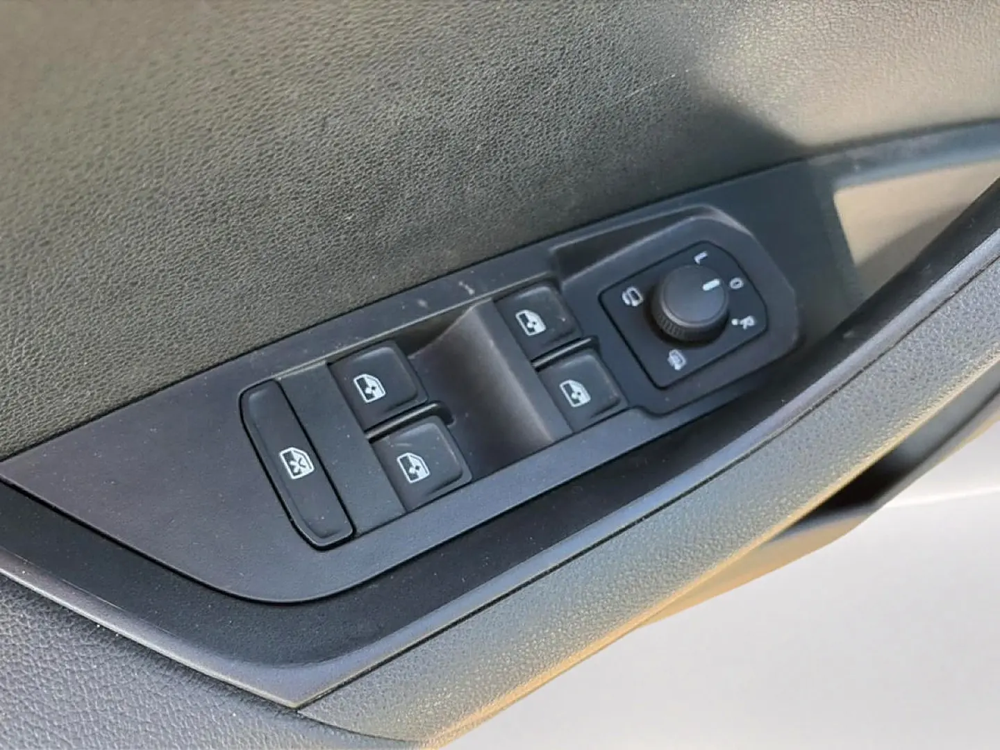 Gros plan sur les commandes des vitres électriques et rétroviseurs côté conducteur du Skoda Karoq gris 2025.