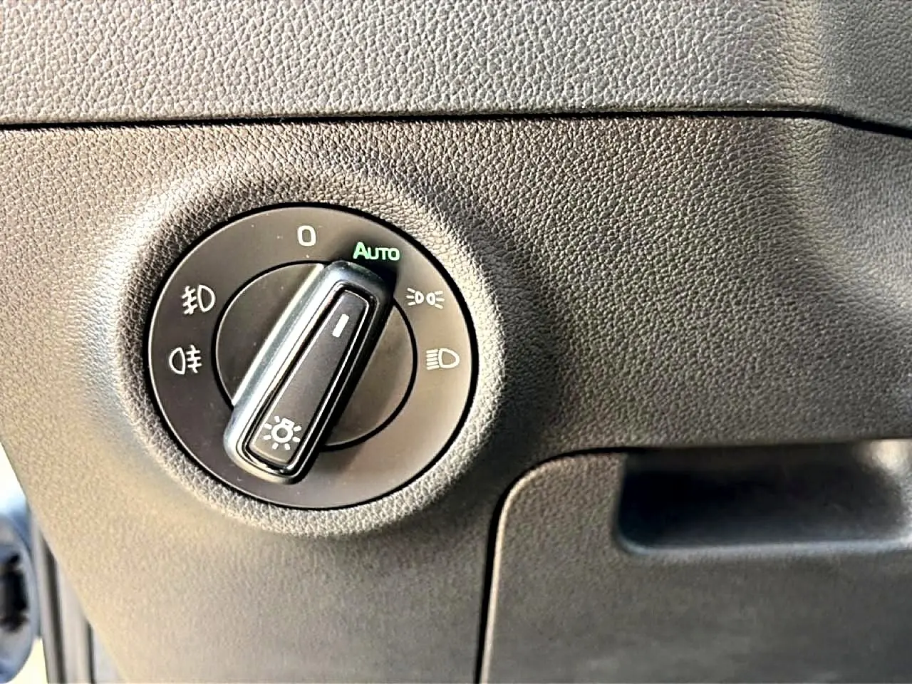 Gros plan sur le bouton de commande des phares dans l’habitacle gris du Skoda Karoq 2025.