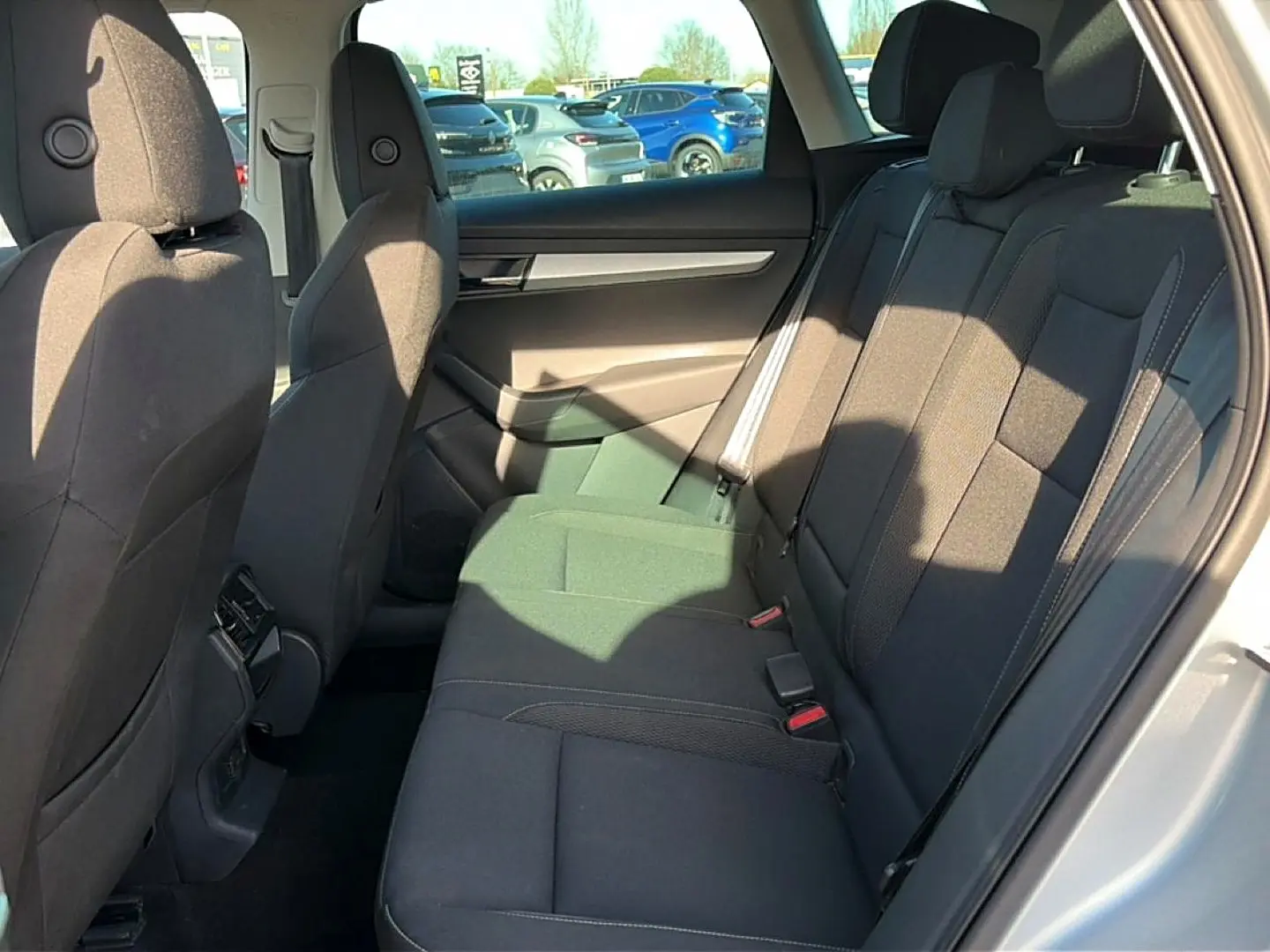 Vue intérieure côté droit des sièges arrière noirs du Skoda Karoq gris 2025 avec appuie-têtes et ceintures visibles.