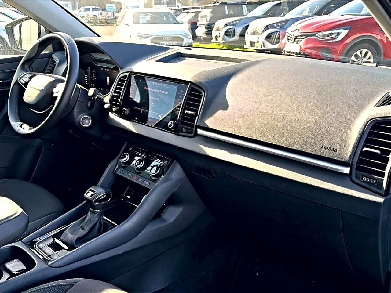 Intérieur avant droit du Skoda Karoq gris 2025, tableau de bord avec écran tactile et volant cuir multifonction.