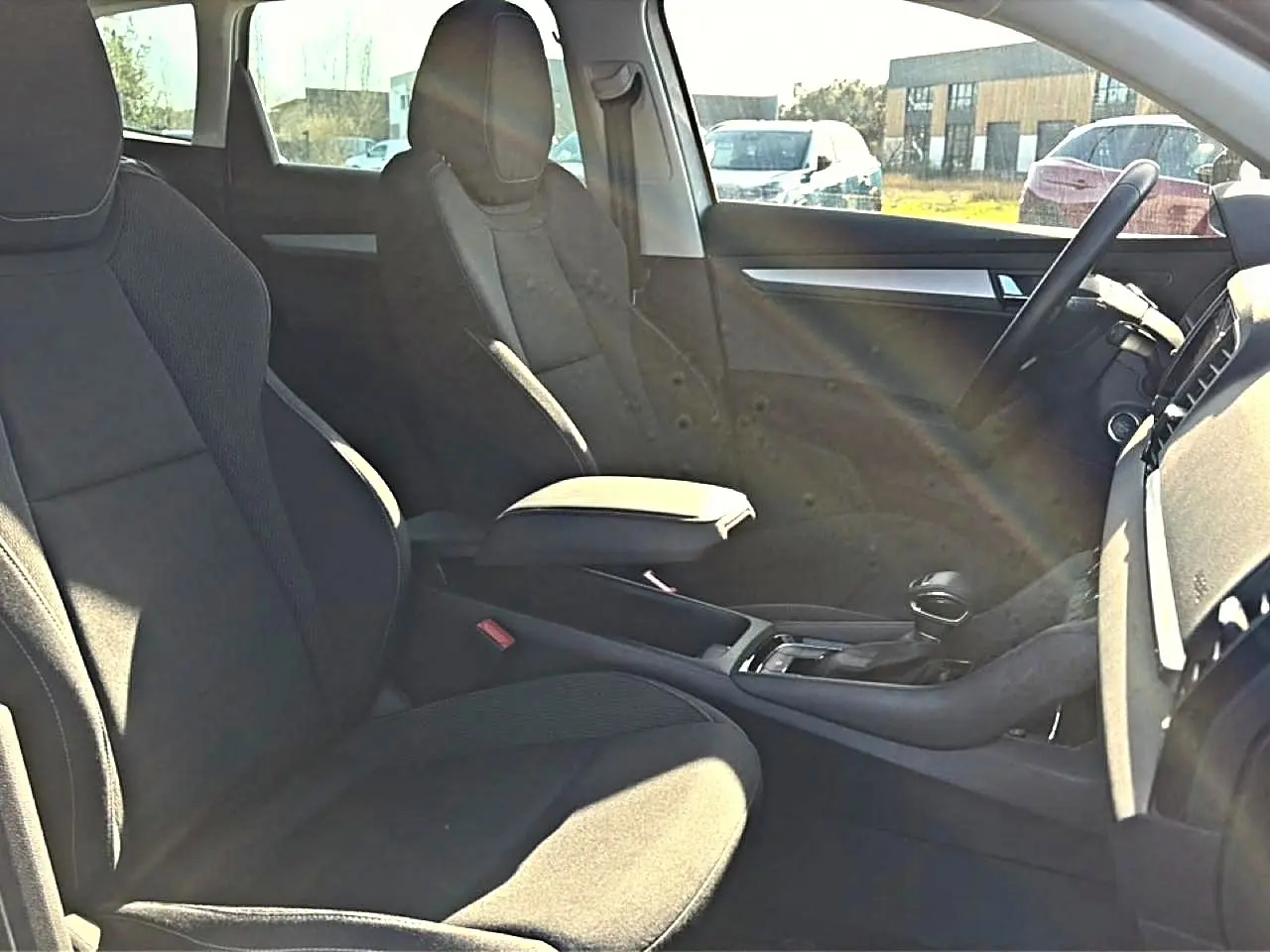Vue intérieure côté droit du Skoda Karoq 2025, sièges noirs avec accoudoir central et volant multifonction.