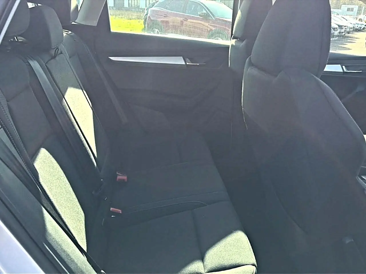 Vue intérieure sur la banquette arrière noire du Skoda Karoq 2025, avec accoudoir central et ceintures visibles.