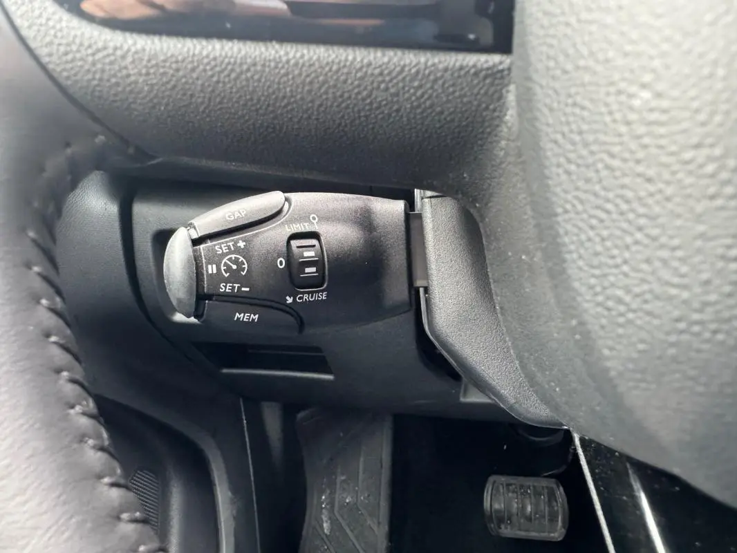 Gros plan sur la commande de régulateur de vitesse au volant d’un Citroën C5 Aircross bleu foncé.