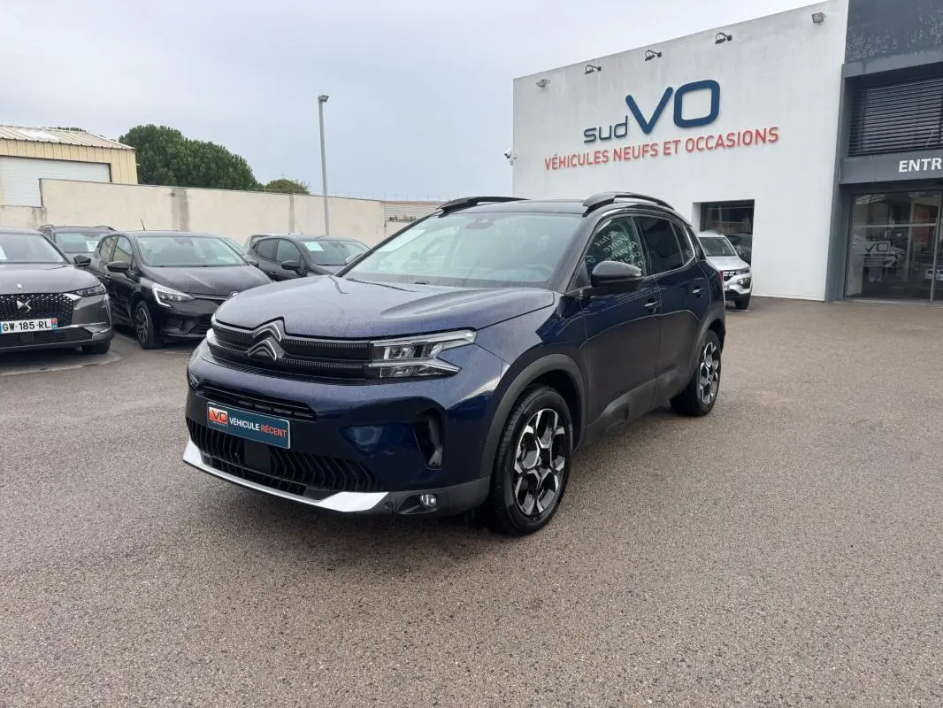 Citroën C5 Aircross hybride bleu foncé en 3/4 avant droit avec barres de toit et jantes alliage 18 pouces.