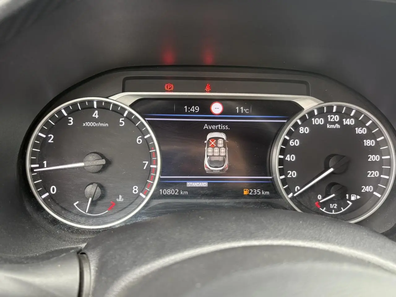 Vue rapprochée du tableau de bord du Nissan Juke blanc perle 2023, affichant les compteurs et l'écran digital.