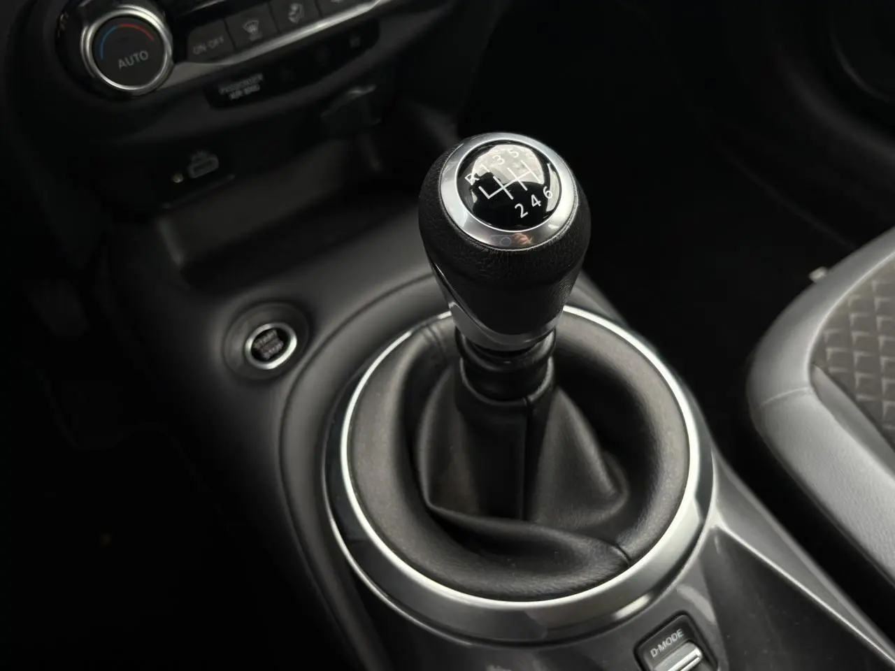 Le levier de vitesses manuel noir du Nissan Juke 2023, avec console centrale et siège partiel gris visible.
