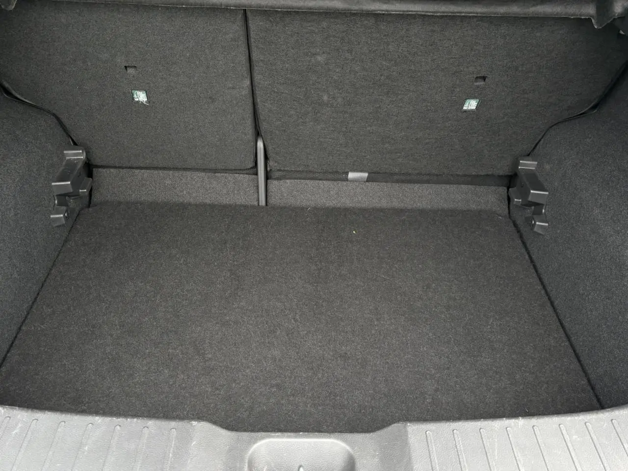 Coffre spacieux et vide du Nissan Juke blanc perle 2023, vue intérieure arrière avec banquette rabattue.