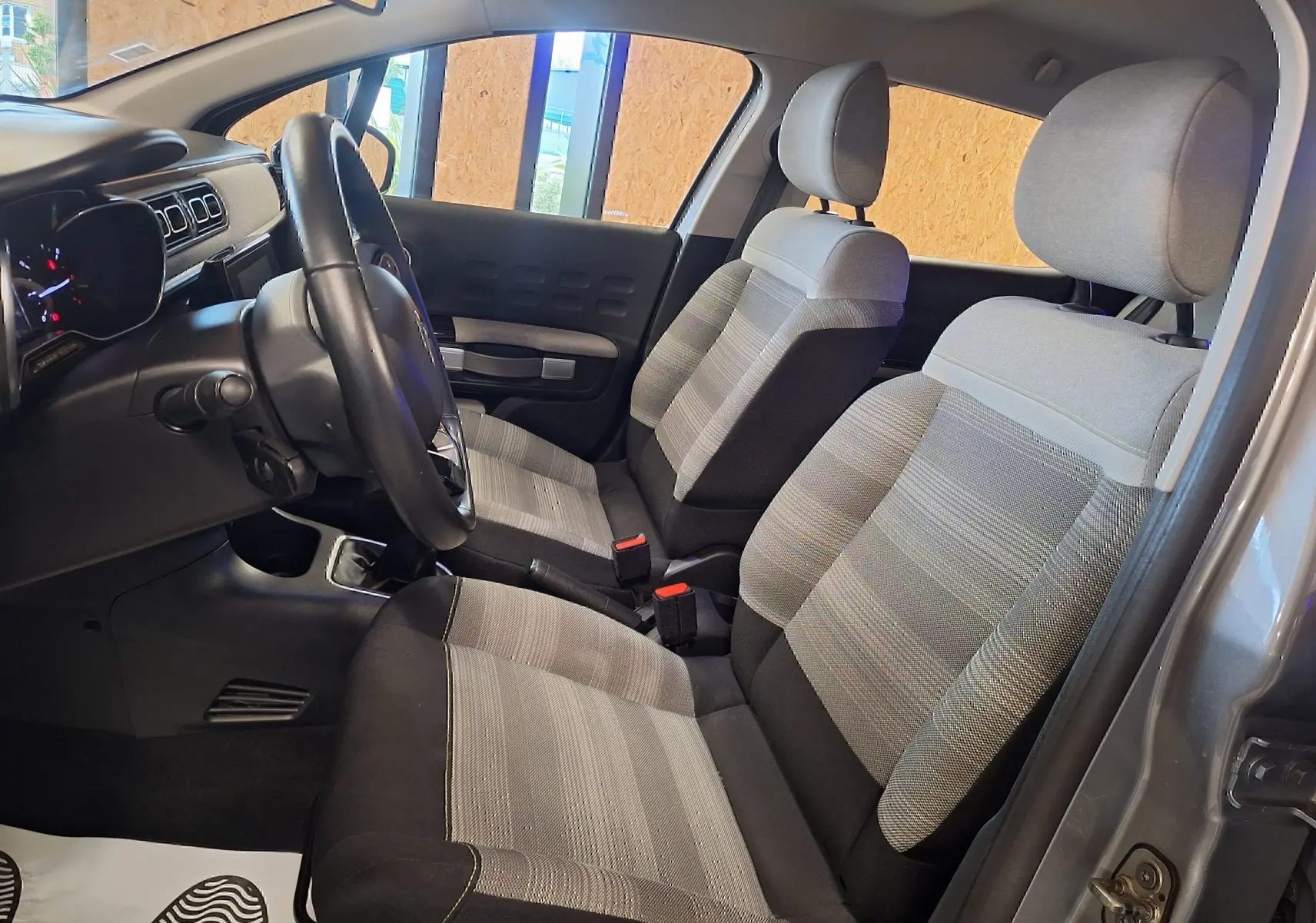 Intérieur de la Citroën C3 1.5 BlueHDi 2019 en tissu Mica Grey, vue côté gauche sur les sièges avant et le volant cuir.