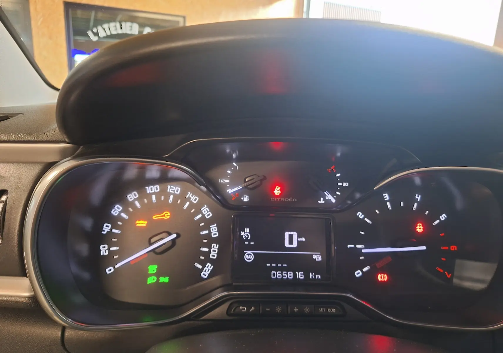 Vue rapprochée du tableau de bord numérique de la Citroën C3 gris, affichant le compteur et plusieurs voyants allumés.