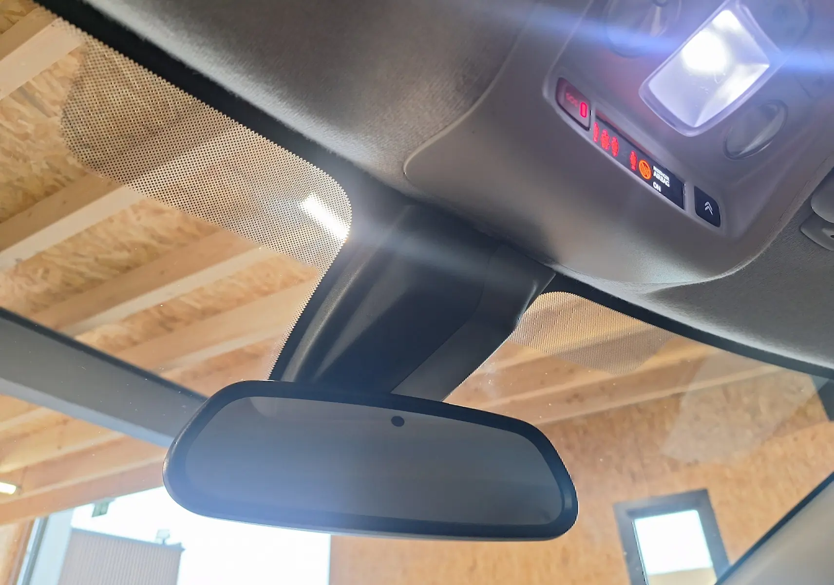 Vue intérieure rapprochée du rétroviseur central et du plafonnier avec éclairage de la Citroën C3 gris 2019.