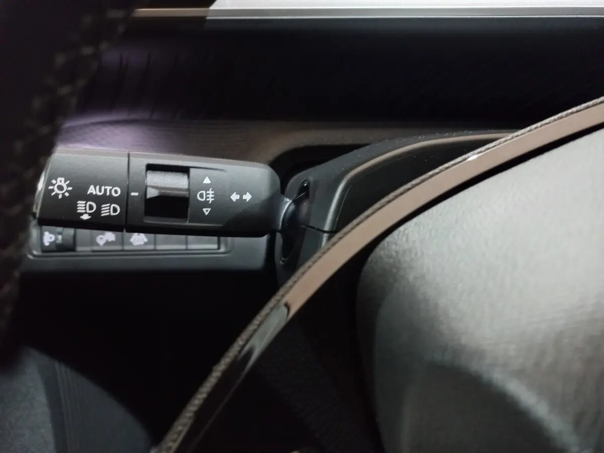 Gros plan sur la commande des feux et clignotants côté gauche du tableau de bord intérieur gris foncé de la Citroën C3 Hybride.