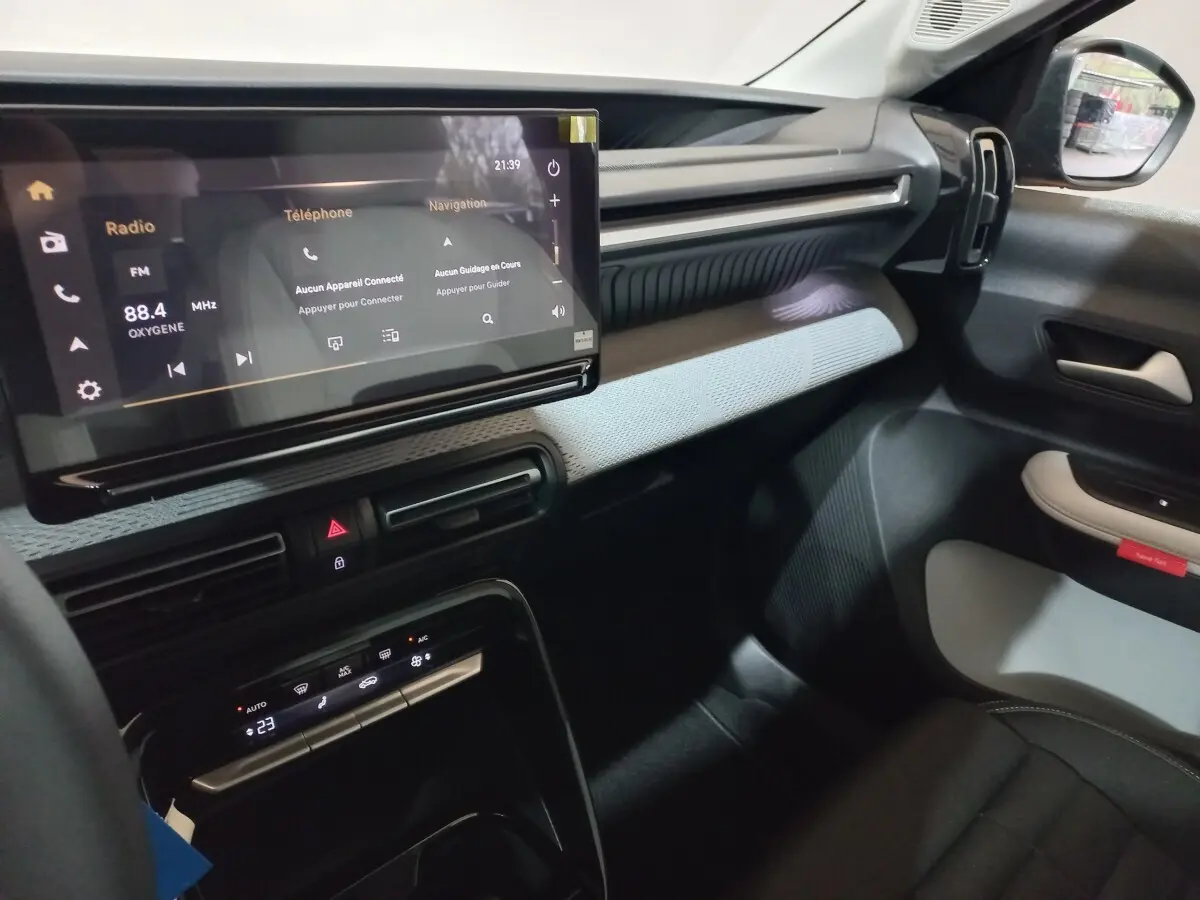 Vue intérieure côté passager de la Citroën C3 hybride gris foncé, avec écran tactile central et tableau de bord moderne.