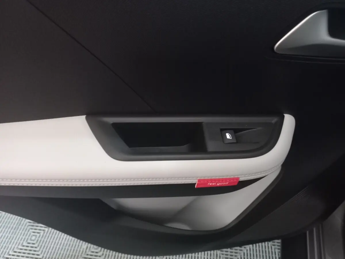 Gros plan sur la poignée intérieure côté gauche de la porte d’une Citroën C3 hybride 2025, garniture noir et gris clair.