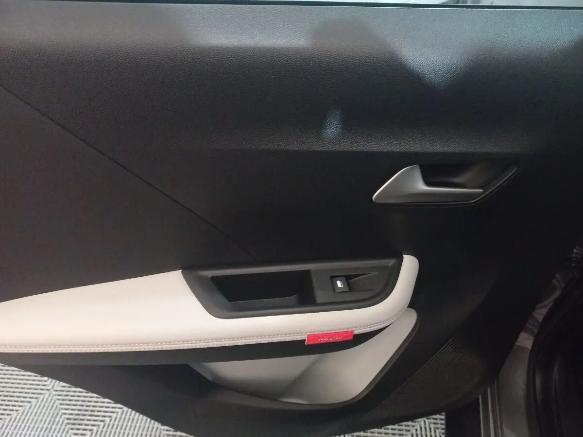 Vue intérieure côté gauche de la porte d'une Citroën C3 hybride 2025 avec garniture noire et beige et bouton de verrouillage.