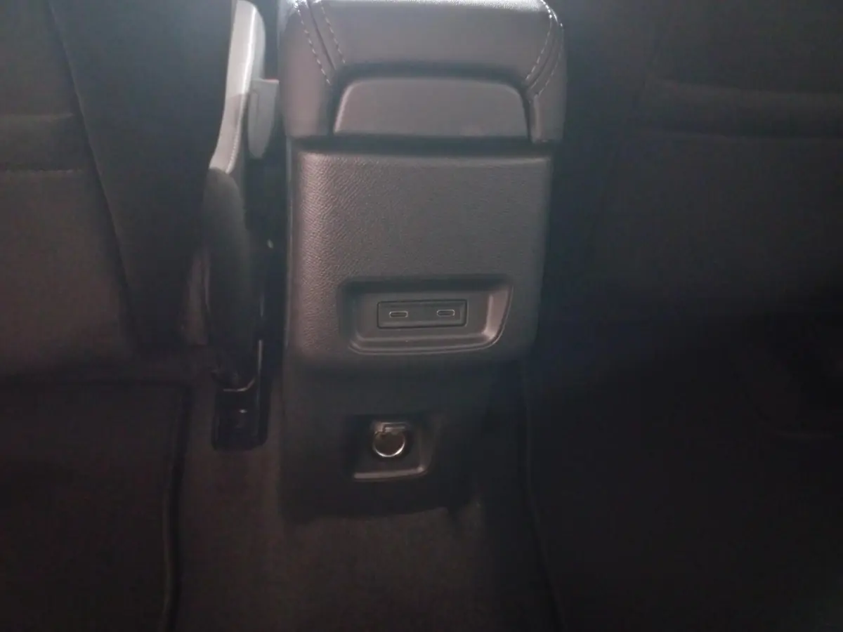 Vue rapprochée de la console arrière noire avec ports USB-C et prise 12V dans l’habitacle de la Citroën C3 hybride gris foncé.