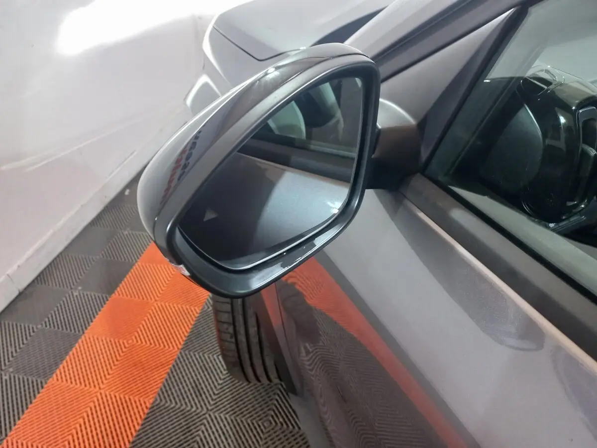 Rétroviseur côté conducteur d'une Citroën C3 hybride gris foncé, vue rapprochée en angle avant gauche.