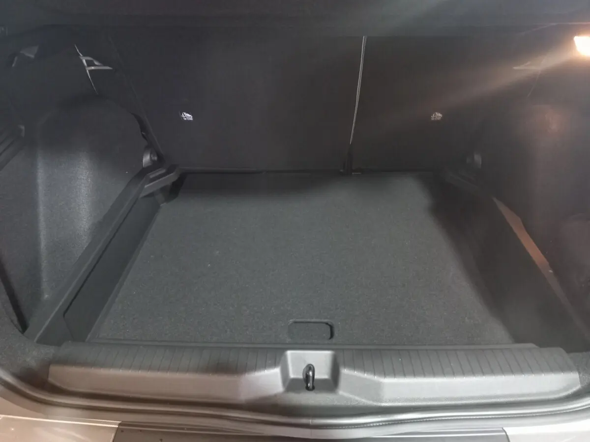 Coffre spacieux de Citroën C3 Hybride gris foncé vu de l'arrière, avec banquette arrière rabattue et éclairage intérieur.