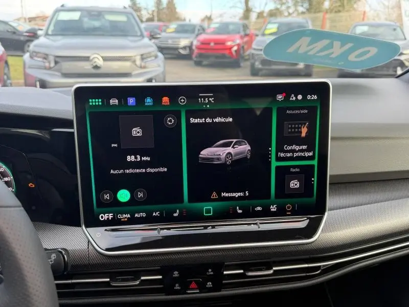 Vue intérieure centrée sur l'écran tactile du tableau de bord de la Volkswagen Golf gris 2025, affichant le statut du véhicule.