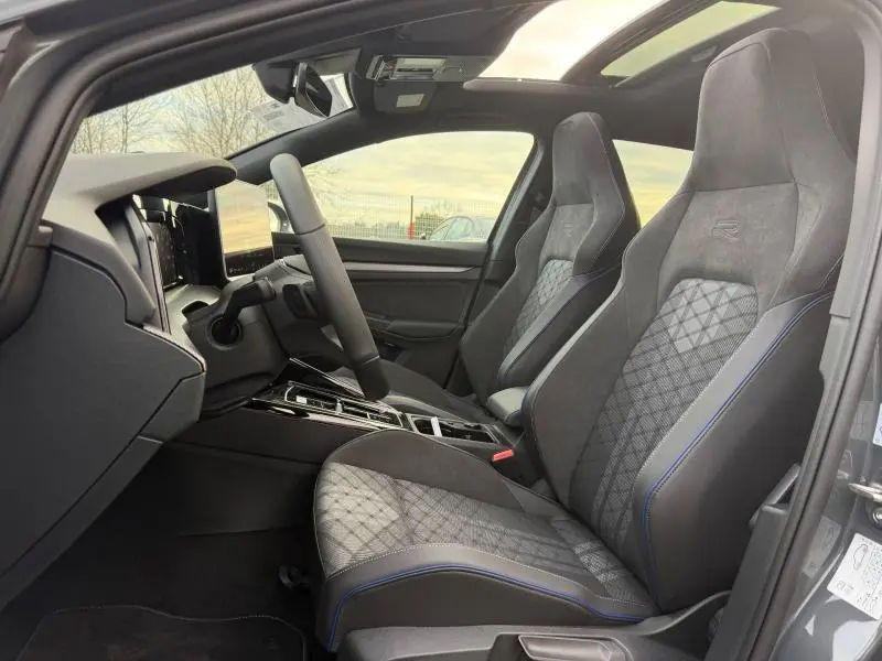 Vue intérieure côté conducteur de la Volkswagen Golf 1.5 eTSI R-Line 2025 avec sièges sport gris et détails bleus.