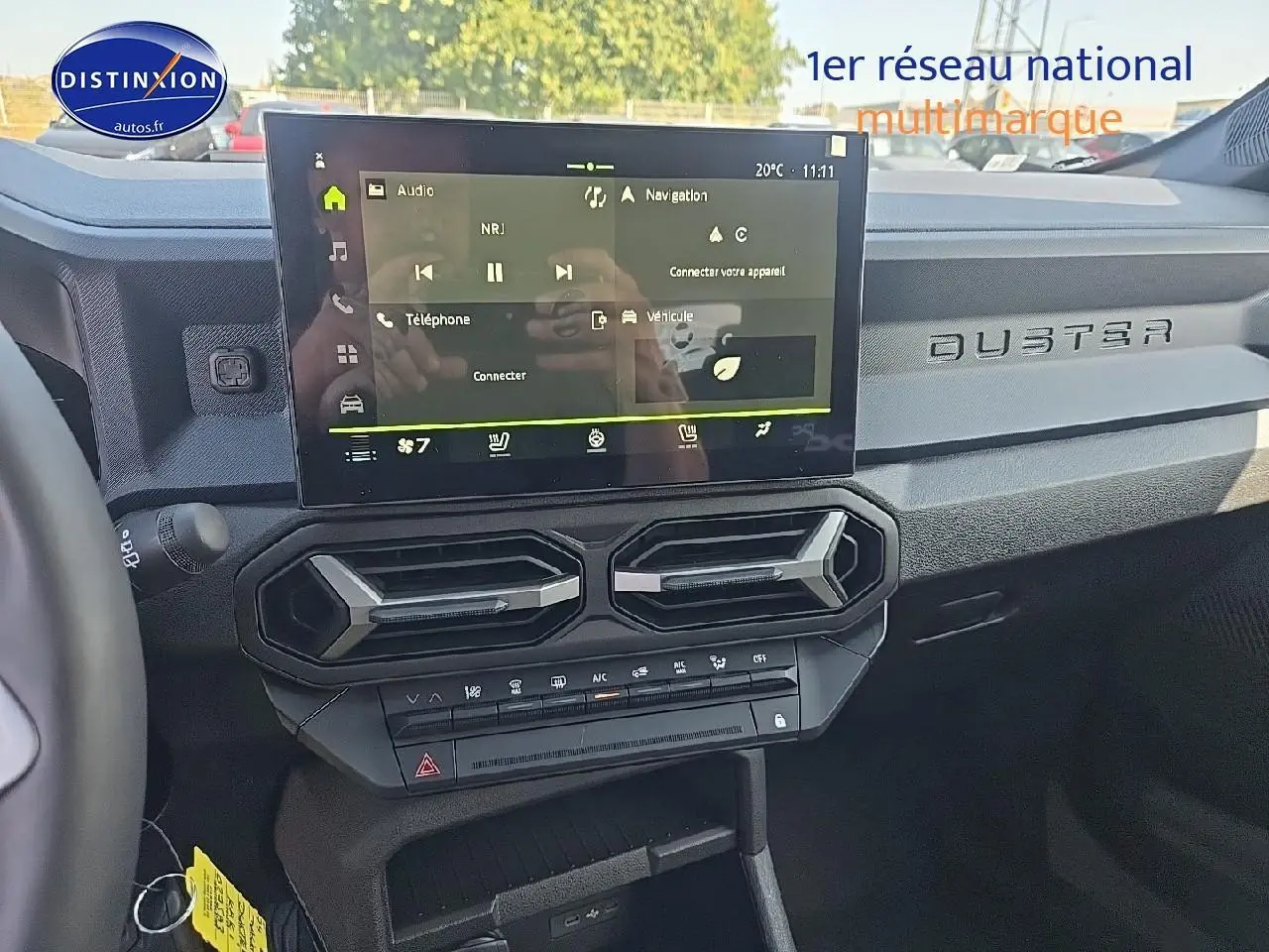 Vue intérieure du tableau de bord du Dacia Duster 2025 avec écran tactile et inscription DUSTER sur la planche de bord.