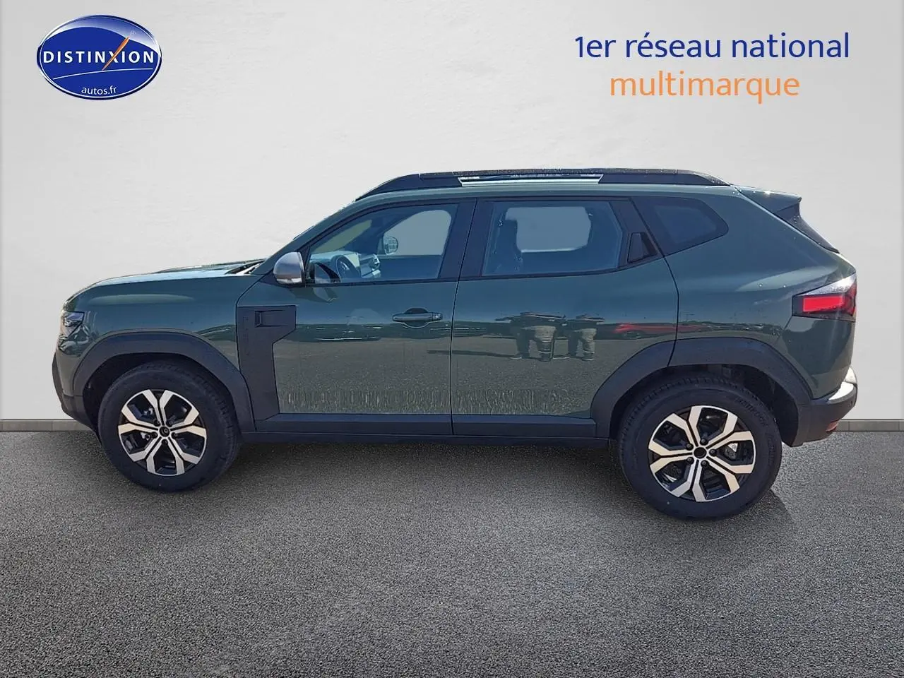Profil côté gauche du SUV Dacia Duster 2025 vert kaki avec jantes alu et barres de toit visibles.